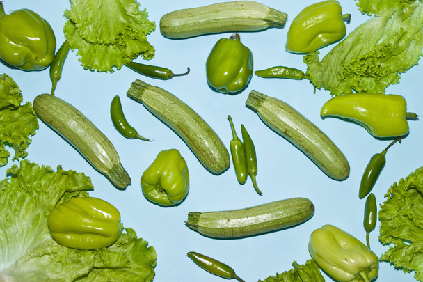 Poivrons courgettes et feuilles de salade sur fond bleu
 - Photo, image