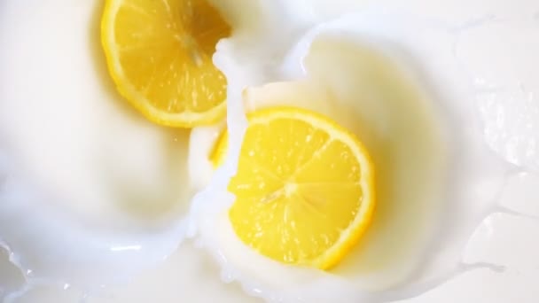 Two lemon pieces drop into milk - Footage, Video
