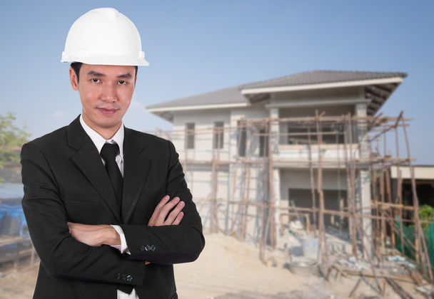 engineer in helmet with arms crossed, house construction backgro - Photo, Image