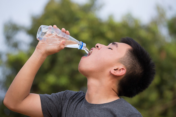 молодой человек или подросток питьевой воды из бутылки
 - Фото, изображение
