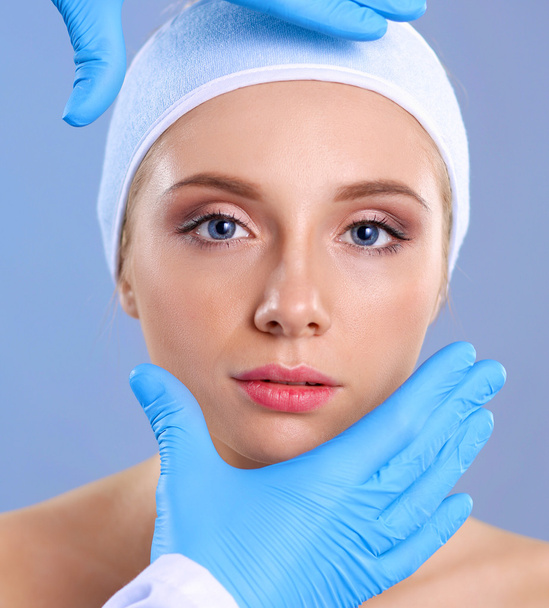 A surgeons hands touching a female face - Foto, Imagem