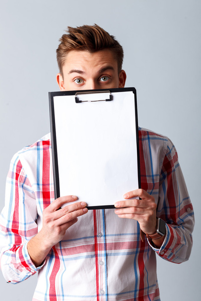 Cute young guy is showing folder of documents - Foto, Imagen