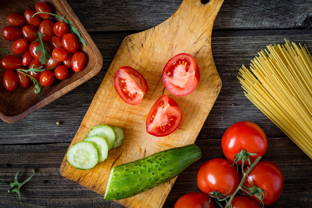 Fresh cooking ingredients on wooden cutting board. Tomatoes and cucumbers - Fotografie, Obrázek