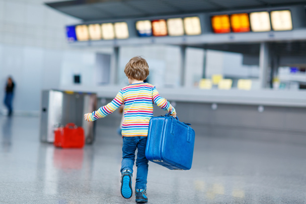 Pikkupoika matkalaukkuineen kansainvälisellä lentokentällä.
 - Valokuva, kuva