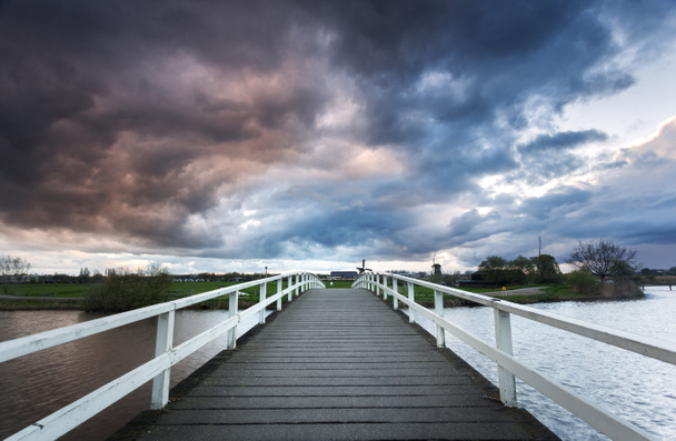 Wooden bridge on the background of dramatic cloudy sky - Valokuva, kuva