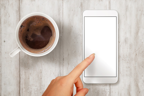 Женщина касается смартфона с изолированным белым экраном для макета. Сцена с видом сверху на кофе
. - Фото, изображение