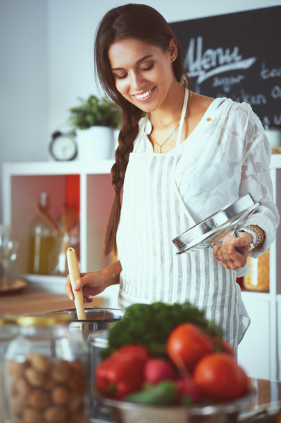 Cooking woman in kitchen with wooden spoon - Photo, image