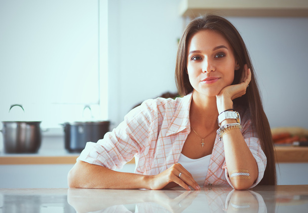 Młoda kobieta siedzi przy biurku w kuchni - Zdjęcie, obraz