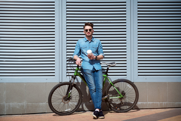Pleasant guy standing with his bicycle - Foto, afbeelding