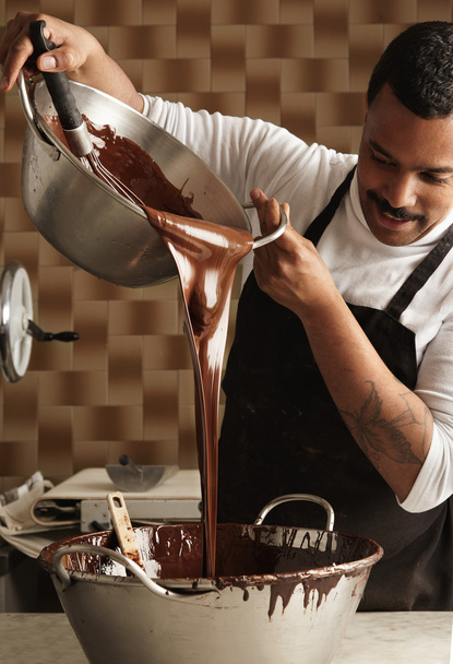 jefe vierte sabroso chocolate derretido de una olla de acero grande a otra
  - Foto, Imagen