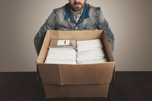 man loader op het werk neemt grote geopende kartonnen doos met witte pakketten - Foto, afbeelding