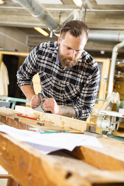 Tischler arbeiten in Werkstatt mit Hobel auf Holzplanke - Foto, Bild