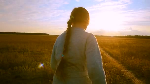 La fille court au coucher du soleil le long de la route et regarde en arrière en riant
 - Séquence, vidéo