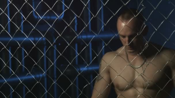 Młody człowiek mięśni poza drut w więzieniu - Materiał filmowy, wideo
