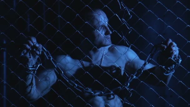 Обнажённый мужчина с металлической цепью за забором
 - Кадры, видео