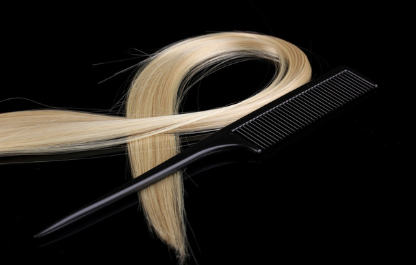 Shiny blond hair and comb isolated on black - Fotoğraf, Görsel
