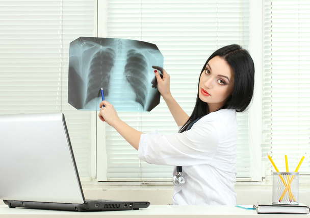 Beautiful girl doctor holding X-ray in the office - Foto, afbeelding