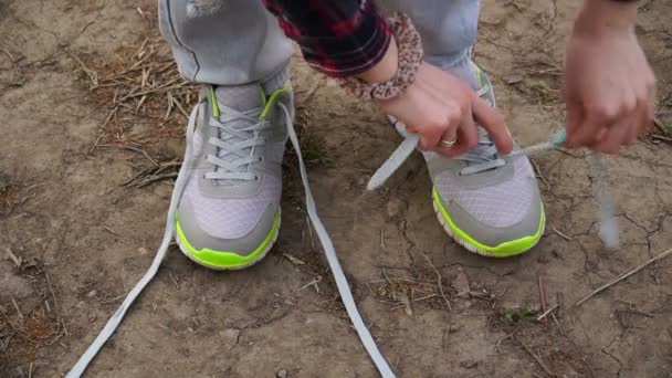 mladá dívka spáchá venkovní chodit a zavázat si tkaničky u bot na tenisky se zastavil. - Záběry, video