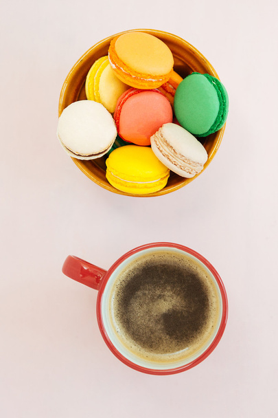 Coffe cup and colorful macaroons on pastel background, top view - Фото, изображение