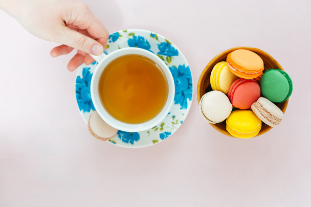 Colorful macaroons with cup of tea on pastel background - Photo, Image