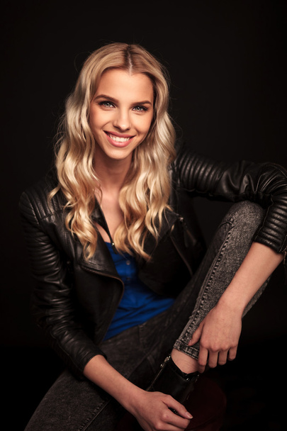 seated young blonde woman in leather jacket laughing  - Foto, Imagen