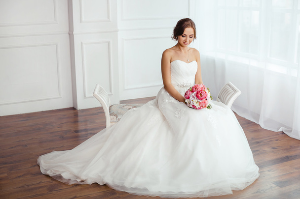 The Bride. Young women with wedding dress in very bright room, - Фото, изображение
