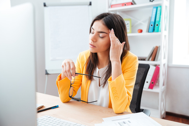 Businesswoman sitting with headache at her workplace - Foto, Imagen