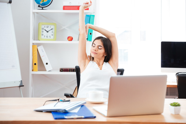 Businesswoman stretching hands in office - Foto, Imagen
