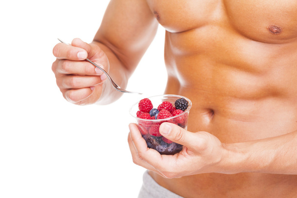 Fit man holding a bowl of fresh fruits - Foto, imagen