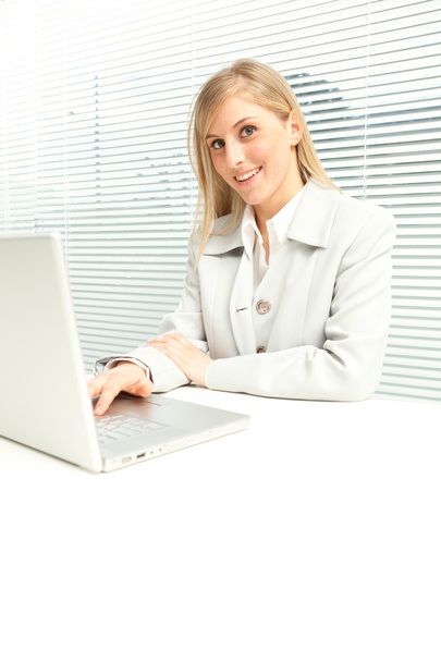 mulher de negócios loira sorridente com laptop perto de janela cega veneziana
 - Foto, Imagem