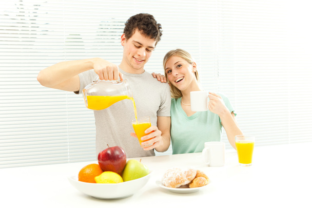 Young casual couple have breakfast with coffee and fruit with venetian blind window - Foto, afbeelding