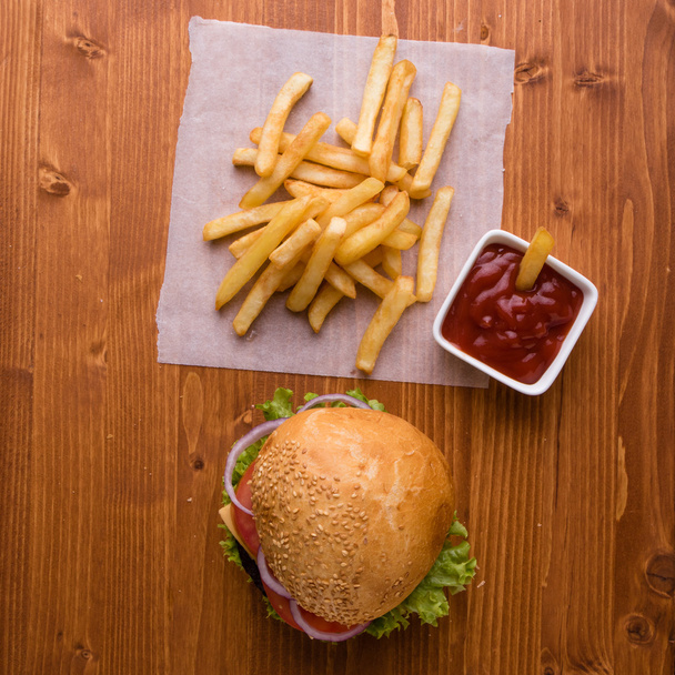 hambúrguer caseiro na mesa de madeira com batatas fritas
 - Foto, Imagem