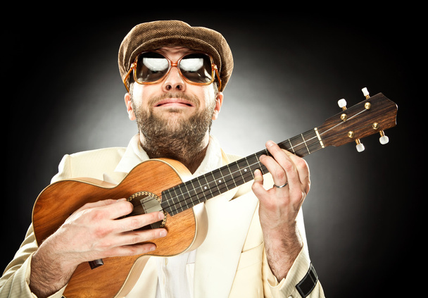 funny man with glasses play guitar ukelele on black background - Foto, Bild