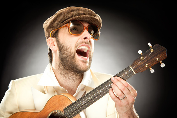 funny man with glasses play guitar ukelele on black background - Fotografie, Obrázek