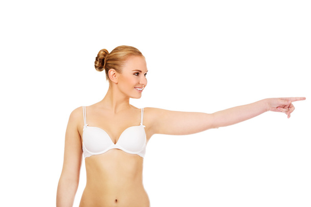 Young woman in white bra pointing for copyspace or something - Foto, Bild