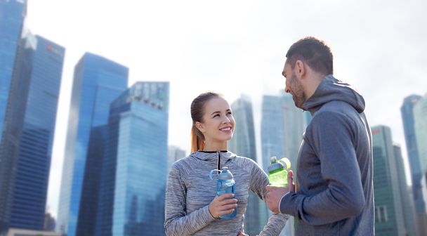 smiling couple with bottles of water outdoors - Photo, image
