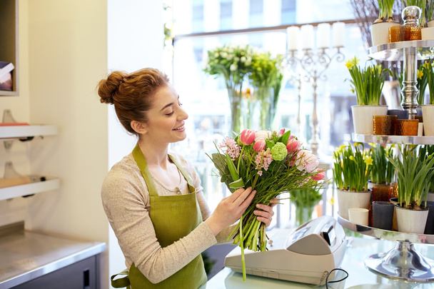 smiling florist woman making bunch at flower shop - Fotó, kép
