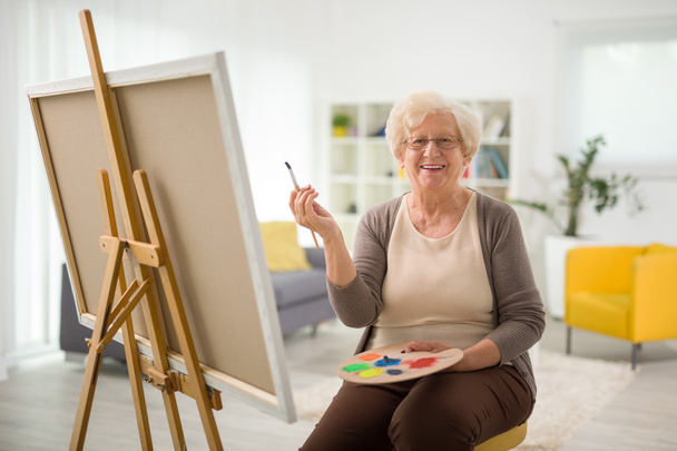 Elderly woman painting on a canvas  - Фото, зображення