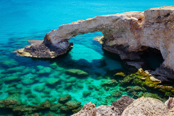 Piękny naturalny łuk skalny w pobliżu Ayia Napa, Cavo Greco i Protaras na wyspie Cypr, Morze Śródziemne. Legendarny most kochanków. Niebieski zielony na morze i słoneczny dzień. - Zdjęcie, obraz