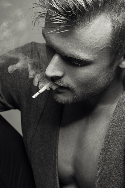  Retrato emotivo del joven modelo de moda fumando cigarrillo. Estilo retro. De cerca. Grabación en blanco y negro
.  - Foto, imagen