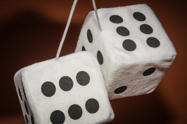 Пара белых плюшевых кубиков, висящих на нитке на коричневом фоне
 - Фото, изображение