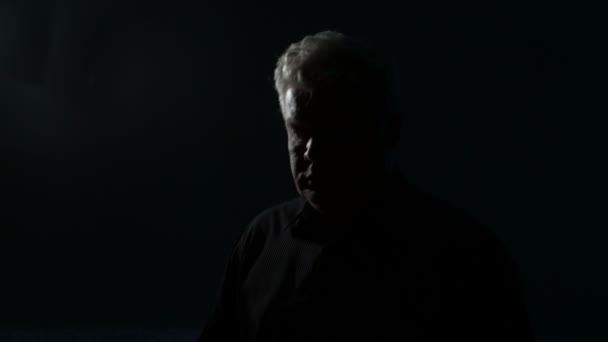 Mężczyzna w średnim wieku w ciemnym pokoju ze świecą - Materiał filmowy, wideo