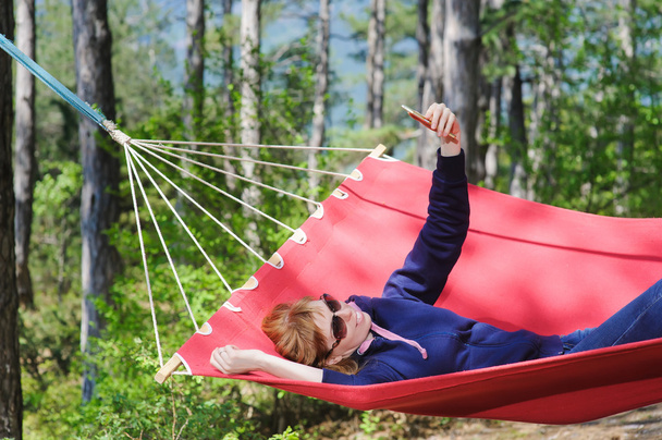 Girl in red hammock, woods - Фото, изображение