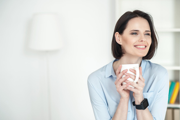 Attractive young woman is drinking hot beverage - Foto, Bild