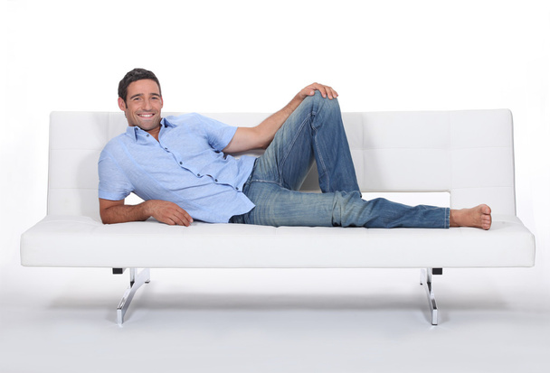 Barefoot man lying on a couch - Фото, зображення