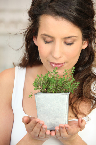 Woman smelling a herb pot - Foto, afbeelding