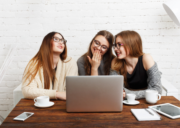 Portrait of three laughing girlfriends with laptop. - Photo, Image