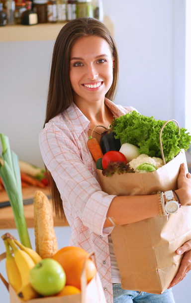 野菜と食料品の買い物袋を持っている若い女性 - 写真・画像