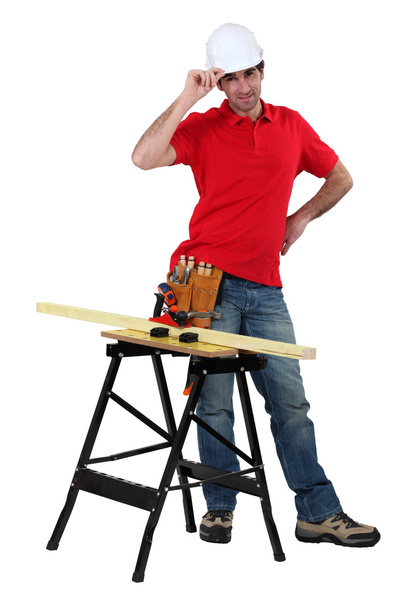 Carpenter stood with plank of wood on workbench - Fotó, kép