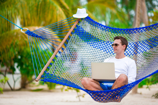 El hombre con el ordenador portátil en la hamaca en vacaciones tropicales
 - Foto, Imagen